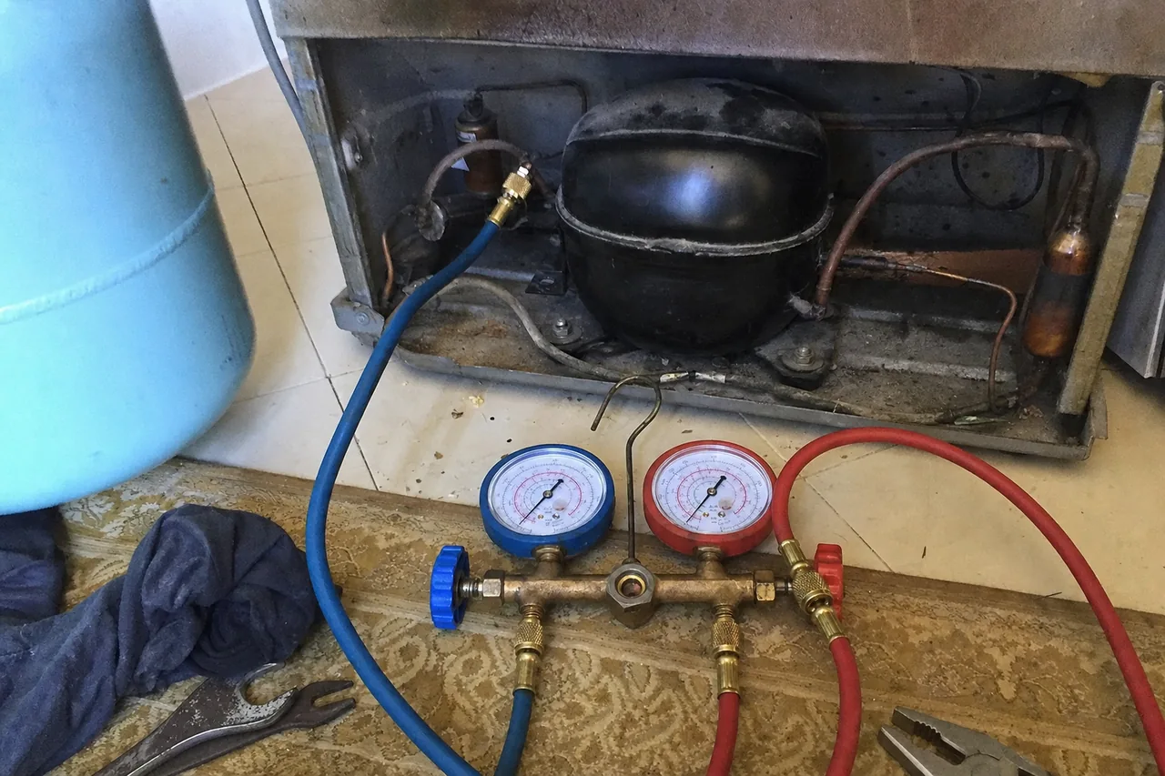 A manifold gauge set connected to a compressor in an open machine compartment, a nitrogen cylinder standing at the left of the frame.